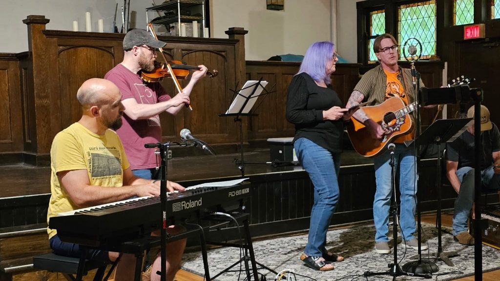 4 musicians performing in a small chapel.